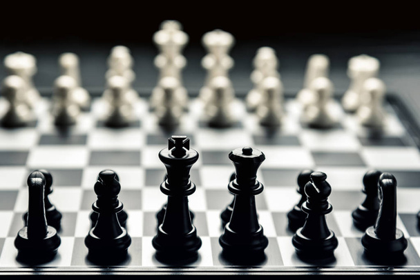 Шахматная доска с черно-белыми шахматами лицом друг к другу. Горизонтальная рамка - Фото, изображение
