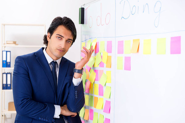 Young handsome employee in front of whiteboard with to-do list   - Photo, Image