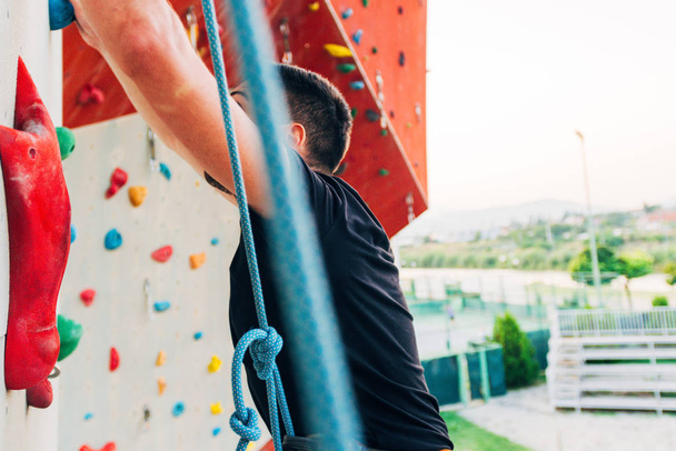 Handsome young man bouldering or rock climbing outdoors - Photo, Image