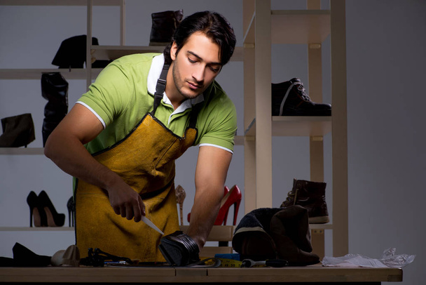 Young shoemaker in workshop at night  - Photo, Image