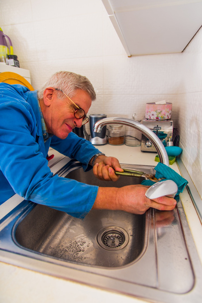 Homme à tout faire principal fixant le robinet de cuisine avec clé
 - Photo, image
