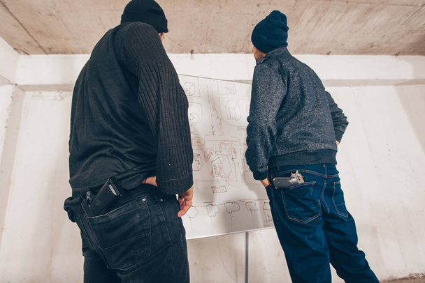 Κλέφτες σχεδιάζουν ένα σχέδιο για το έγκλημα στο χάρτη στο υπόγειο - Φωτογραφία, εικόνα