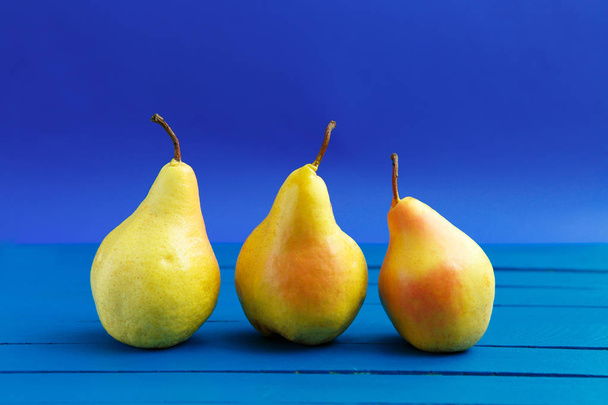 Pear decoration stock images. Yellow pear on blue background. Pear home decor. Yellow decorative pear - Fotó, kép