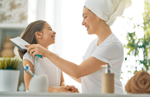 Happy family! Mother and daughter child girl are combing hair in the bathroom. - Foto, Bild