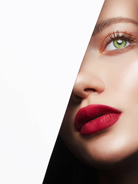 beautiful woman with a makeup, into the hole of white paper. make-up artist concept. beauty girl with beautiful bright green eyes and red Lips - Photo, Image
