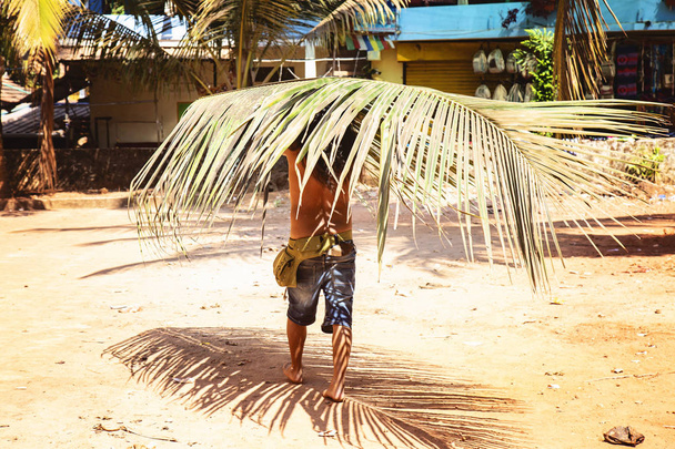 Başının üstünde bir palmiye yaprağı taşıyan adam - Fotoğraf, Görsel