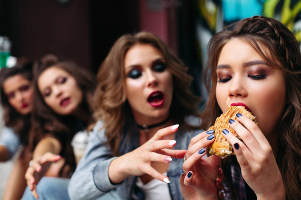 Friends eating fast food against graffiti. - Valokuva, kuva