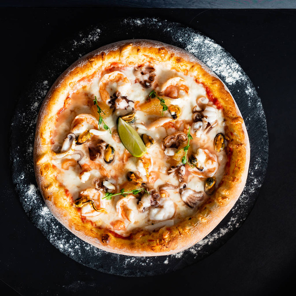 sefood pizza on the black background - Zdjęcie, obraz