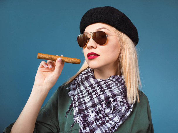 Porträt einer blonden schönen Frau mit Hut und Sonnenbrille mit Zigarre im kubanischen Guevara-Stil  - Foto, Bild