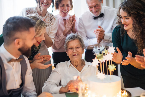 An elderly woman with multigeneration family celebrating birthday on indoor party. - Photo, Image