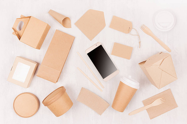 Blank different cardboard packaging for fast food - coffee cup, screen phone, cutlery, sugar, spice, container and box for sushi, noodles on white wood board. - Photo, image