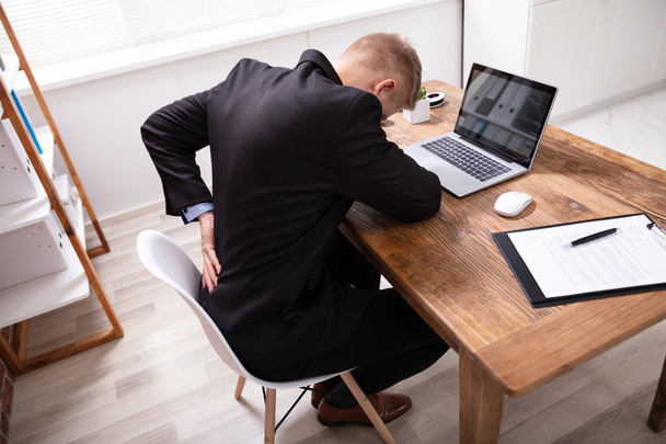Knappe jonge man Executive met rugpijn werken op laptop in Office - Foto, afbeelding