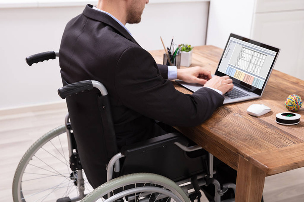 Disabled Businessman Sitting On Wheelchair Using Laptop At Workplace - Fotoğraf, Görsel