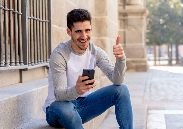 Ευτυχισμένος φοιτητής του φλερτ και χρονολόγηση σε απευθείας σύνδεση και αποστολή μηνύματος κειμένου, χρησιμοποιώντας έξυπνο τηλέφωνο ενώ ταξιδεύετε ή σπουδάζουν σε μια ευρωπαϊκή πόλη. Κοινωνικό δίκτυο, το κινητό εφαρμογές και dating sites έννοια - Φωτογραφία, εικόνα
