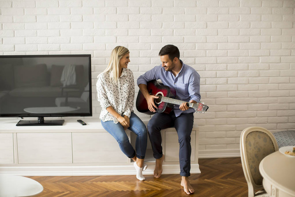 Amour jeune couple avec guitare dans la chambre à la maison
 - Photo, image