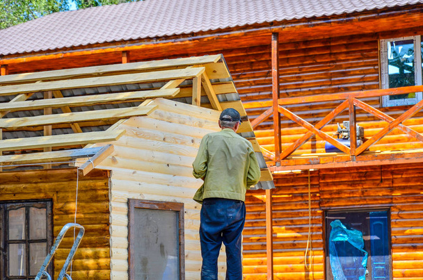 Εργαζόμενος, ξυλουργός και οικοδόμος φτιάχνοντας ένα σπίτι από το πλαίσιο ενός ξύλινου δοκού. - Φωτογραφία, εικόνα