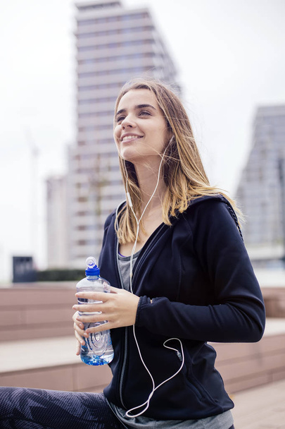 Mladá žena je osvěžující po cvičení a pití vody v přírodě - Fotografie, Obrázek
