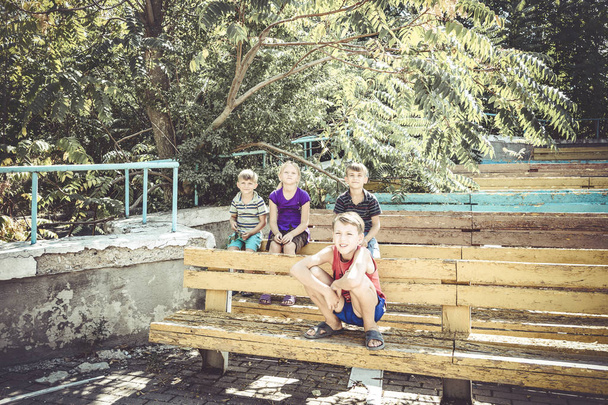 Orvot lapset istuvat hylätyssä puistossa vanhoilla penkeillä.
 - Valokuva, kuva