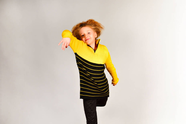 A menina de esportes pula em direções diferentes em um fundo cinza, uma foto em um salto, o cabelo levanta-se
 - Foto, Imagem