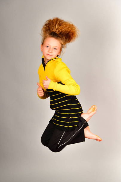 Sportovní dívka skáče různými směry na šedém pozadí, na fotografii v skoku, vlasy stoupá - Fotografie, Obrázek