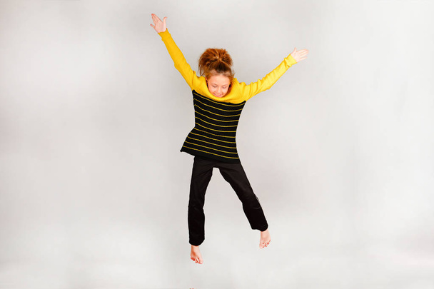 Το κορίτσι πηδάει πάνω, χέρια και πόδια σε διαφορετικές κατευθύνσεις. - Φωτογραφία, εικόνα