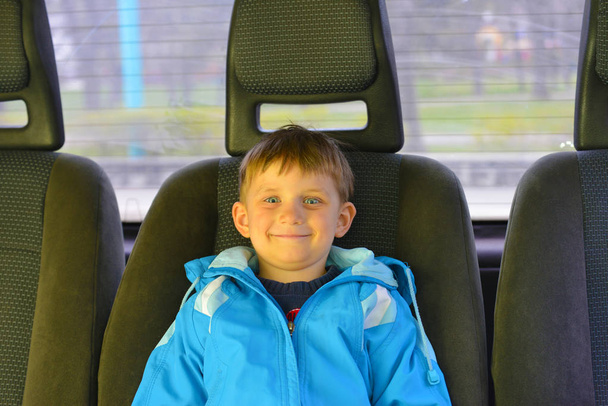 Le garçon est assis sur le siège arrière dans la voiture
 - Photo, image