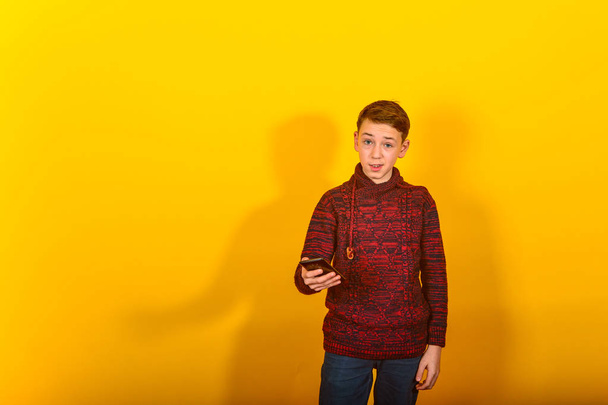 Boy with a smartphone on a yellow background - Photo, Image