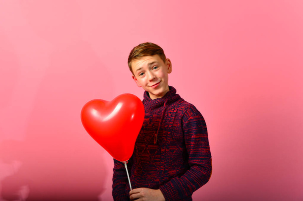 Chłopiec wśród czerwonych balonów serca w kształcie serca na różowym tle na Walentynki i 8 marca. - Zdjęcie, obraz