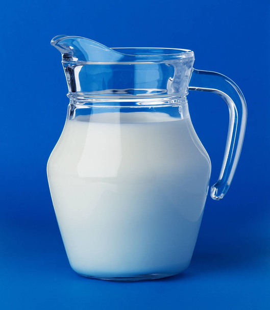Üveg kanna tej elszigetelt kék háttér - Fotó, kép