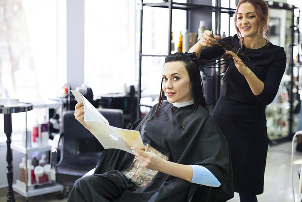 Profesjonalny salon fryzjerski przygotowania do nadania jej piękny wesoły kobieta klienta czesanie jej włosy fryzura. Usługi branży uroda  - Zdjęcie, obraz