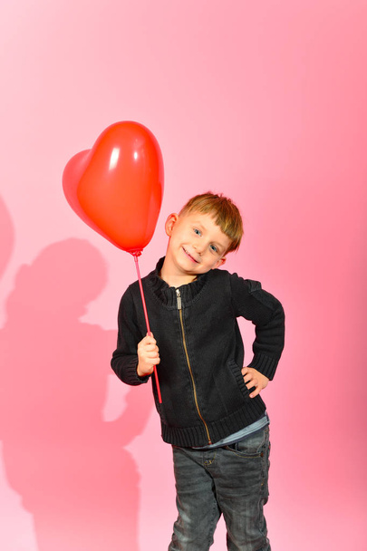 Симпатичный ребенок держит в руке воздушное сердце в качестве подарка
. - Фото, изображение