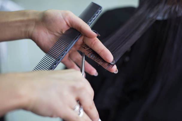 Парикмахер стрижет волосы клиента в салоне красоты. Концепция красоты. Закрыть
 - Фото, изображение