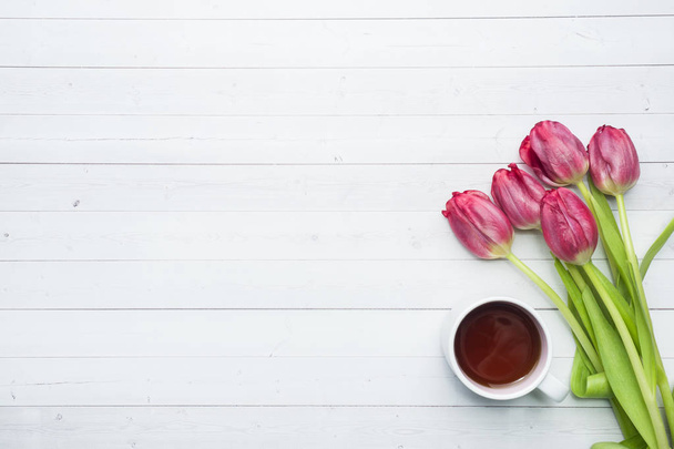 Overhead view of a bouquet of tulips and a Cup of coffee. copy space. Flat lay, top view. - Photo, image