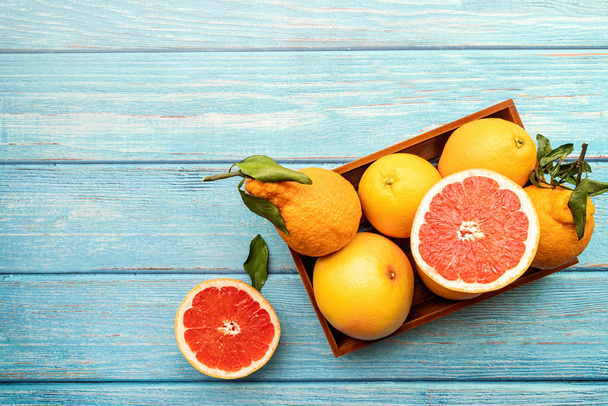 フラット ブルーの素朴な背景に木製の箱に様々 な柑橘系の果物を置く上面図 - 写真・画像