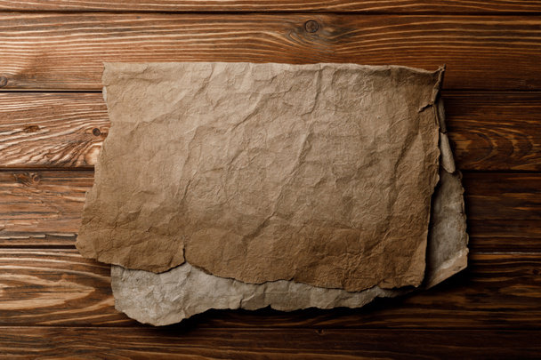 brown old parchment sheet lying on wooden background - Foto, Imagen