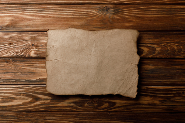 hnědý starý pergamen papír ležící na dřevěné pozadí - Fotografie, Obrázek