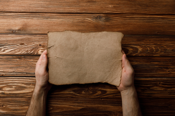 top view of man holding aged paper sheet in hands  - Foto, Imagen