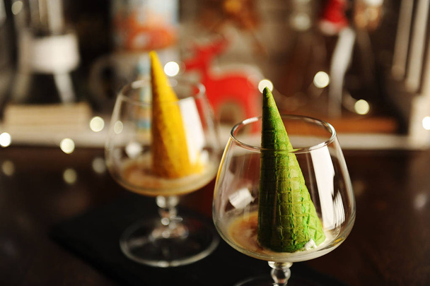 Food styling of Italian dessert afogato in the form of a Christmas tree with a shining star. Inverted green waffle cone in brandy glass - Photo, Image