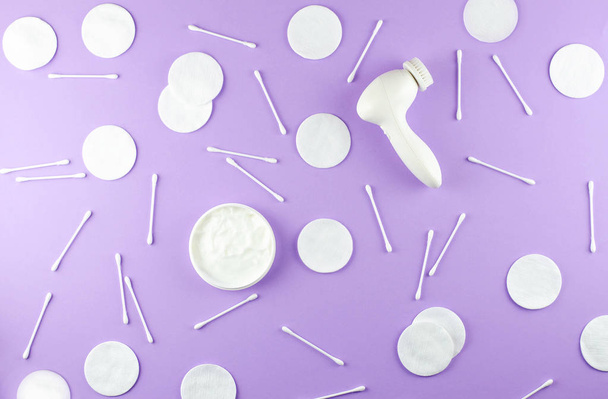 Care cosmetics and beauty accessories on a light purple background. Namely: cotton pads, cotton swabs and a massager for cleaning the face. - Foto, Imagem