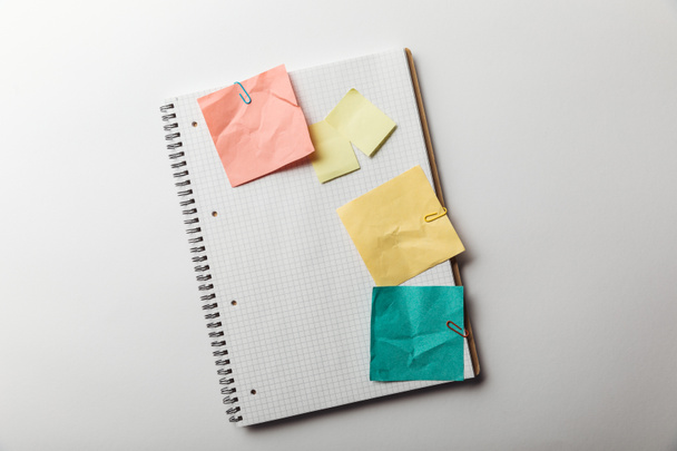 top view of notebook with blank squared page near crumpled sticky notes on white background - 写真・画像