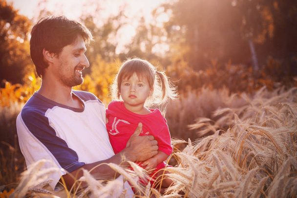 黒い髪と髭を持つ若いお父さんは、穀物のフィールドに 3 年間娘を保持します。 - 写真・画像