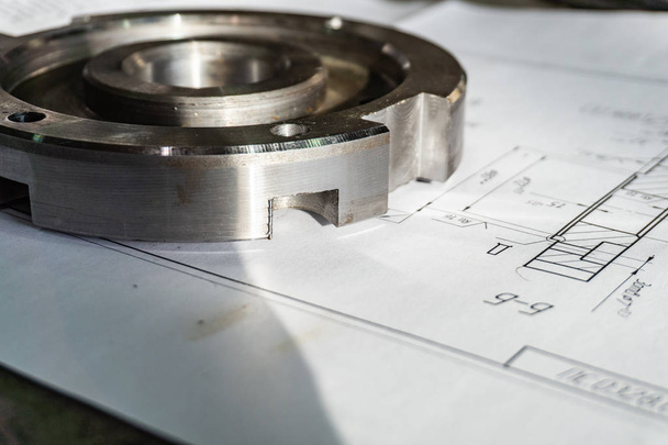The transition flange after processing lies on the technical drawing. Detail ready to work with a drawing together in mechanical engineering - Photo, Image