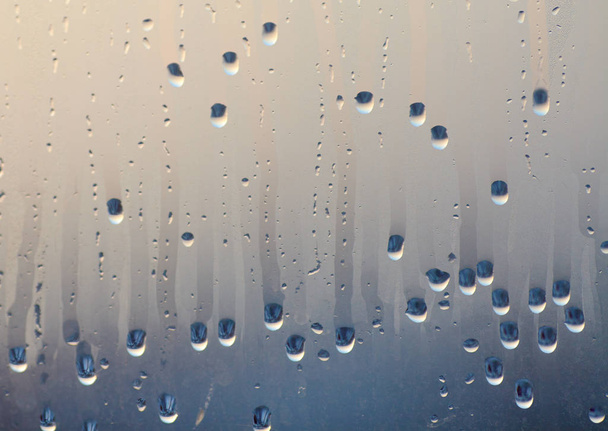 Druipende druppels van het gecondenseerde water op het glas. Achtergrond van het natuurlijke water bundeling van venster condensatie - Foto, afbeelding