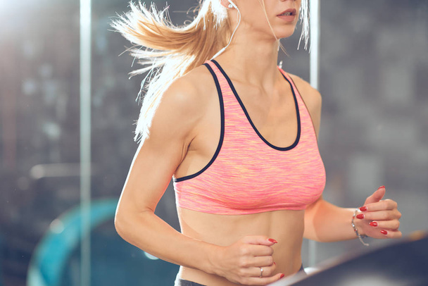 Woman running on treadmill. Close up of woman's torso. Healthy lifestyle concept. - Photo, Image