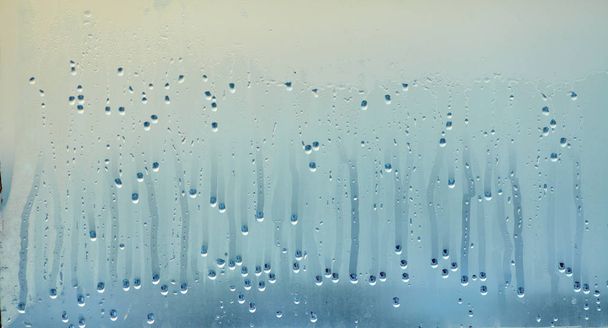 Dripping drops of condensed water on the glass. Background of natural water pooling from window condensation - Photo, Image