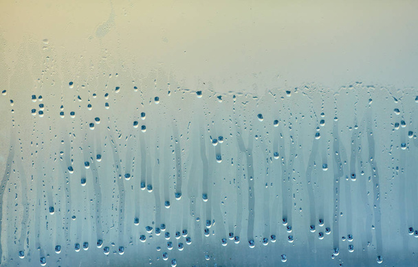Dripping drops of condensed water on the glass. Background of natural water pooling from window condensation - Photo, Image