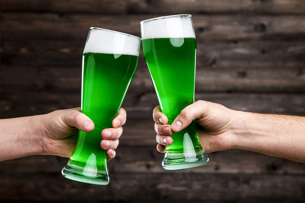 聖パトリックの日。木製の背景に男性の手に緑色のビールのグラス - 写真・画像