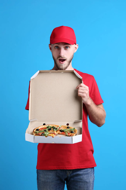 Delivery man with pizza in cardboard box on blue background - Fotografie, Obrázek