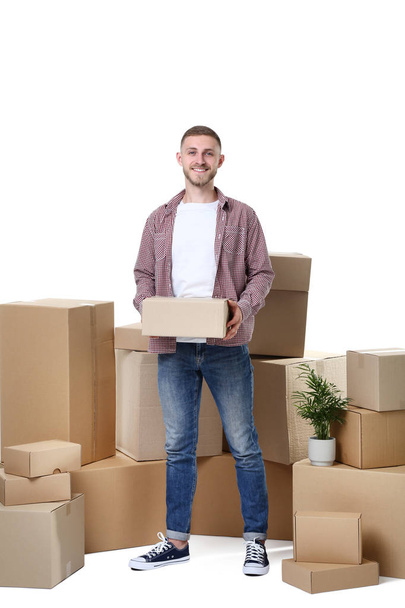 Young man with cardboard boxes on white background - Zdjęcie, obraz