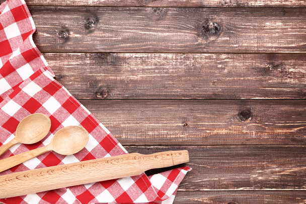 Wooden cutlery with red napkin on brown table - Фото, зображення